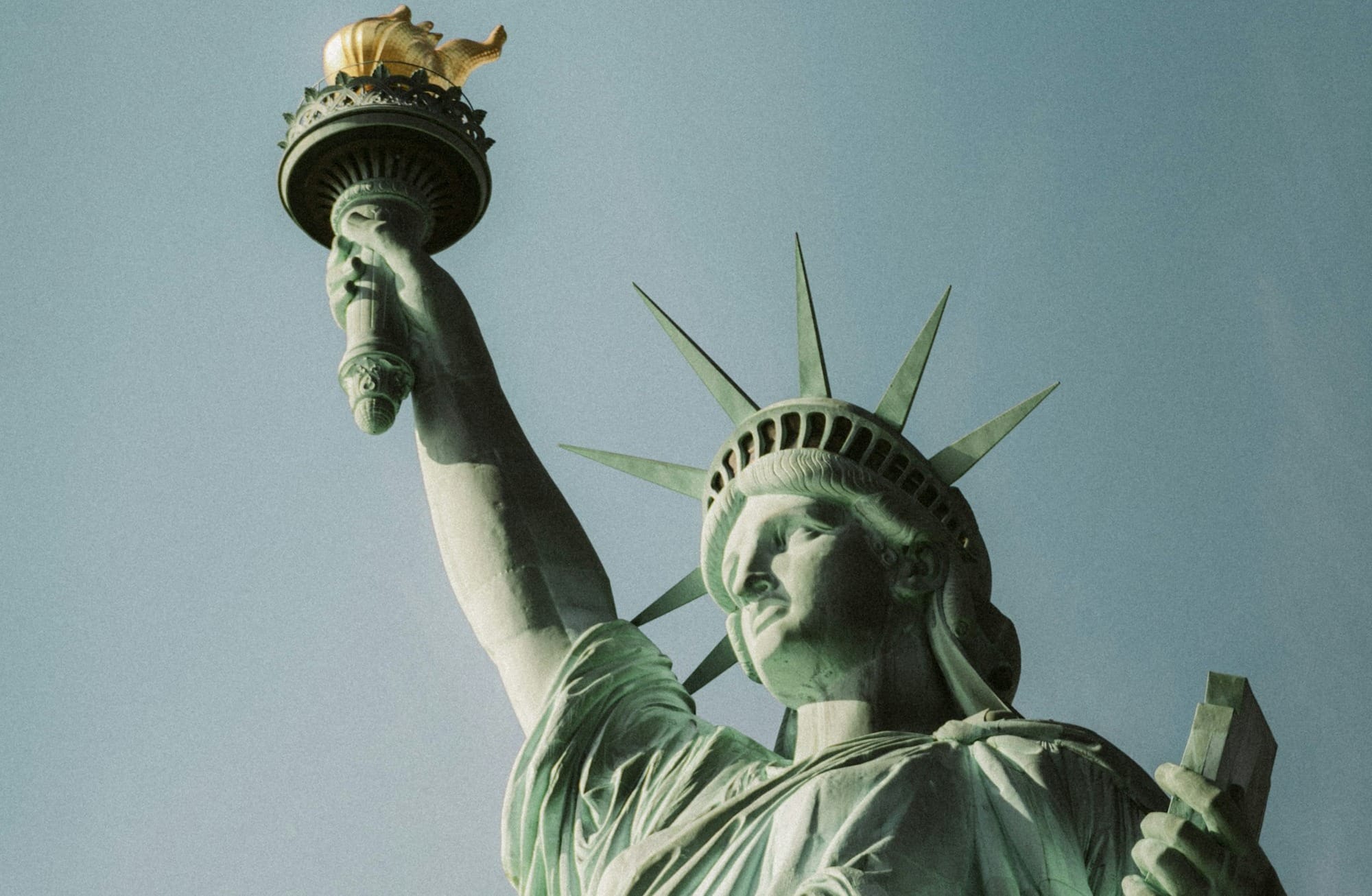 The statue of liberty is holding a bird in its hand